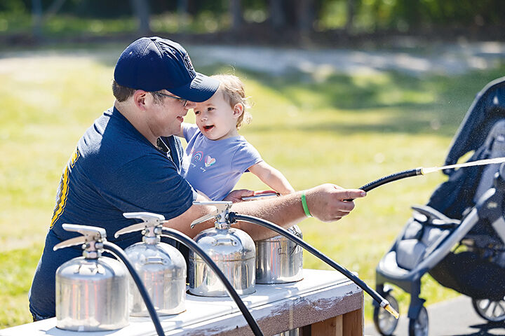 Cedar Hill Fire Protection District Capt. Michael Wittu uses a fire extinguisher with his daughter Edith, 18 months, on Sept. 6 at the Cedar Hill Fire Protection District’s 75th anniversary celebration.